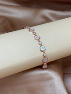 Rose gold bracelet with floral designs on a beige ribbon against a satin background